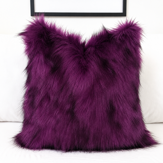 Deep purple faux fur pillow cover with black-tipped long pile, styled on a white sofa for gothic and Halloween home decor