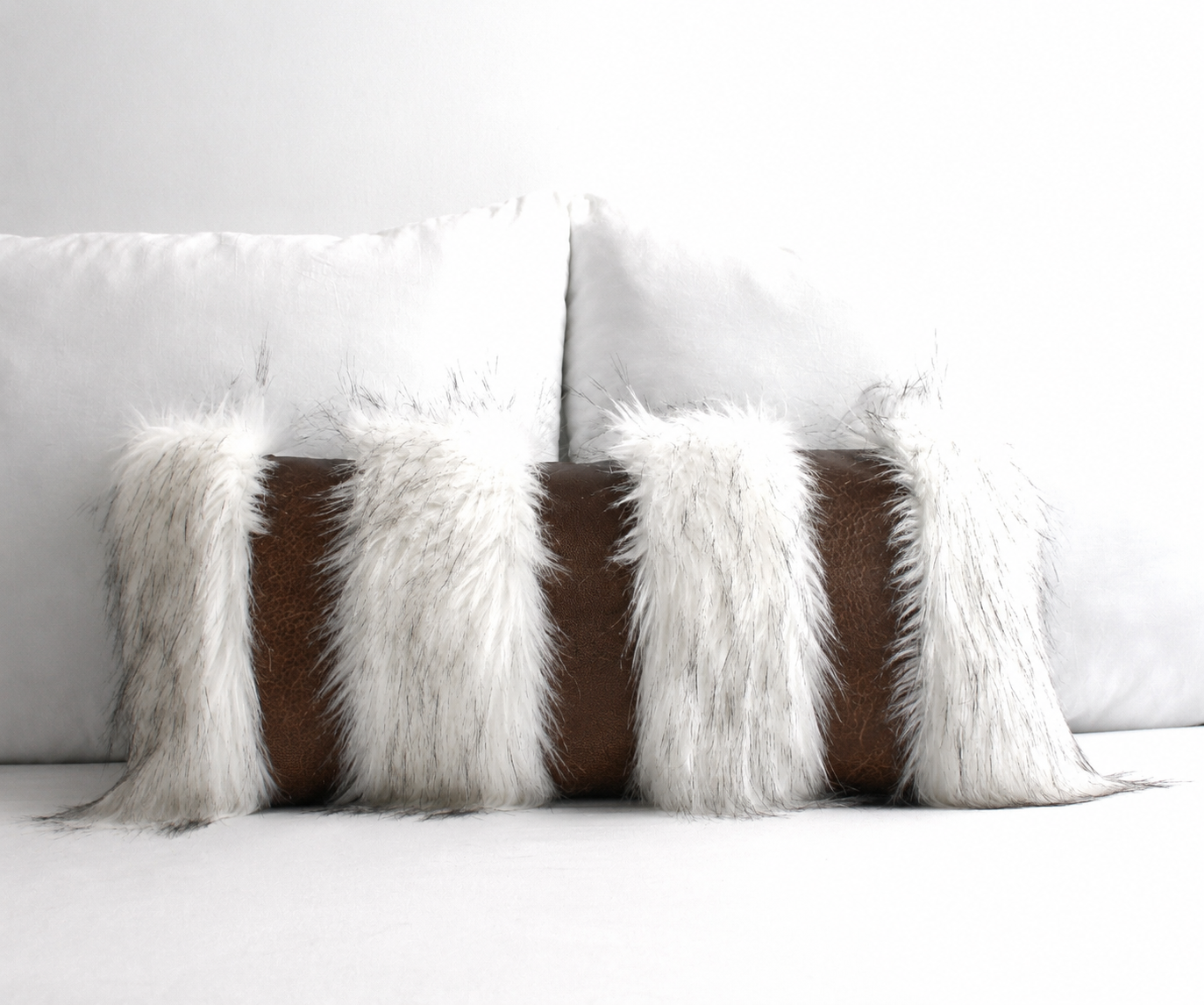 Chestnut brown faux leather and Snow Fox faux fur luxury throw pillow styled on a white sofa