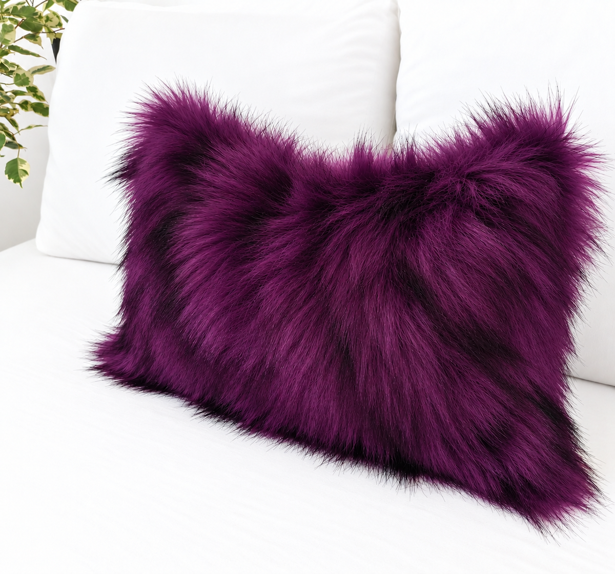 Deep purple faux fur pillow cover with black-tipped long pile, styled on a white sofa for gothic and Halloween home decor
