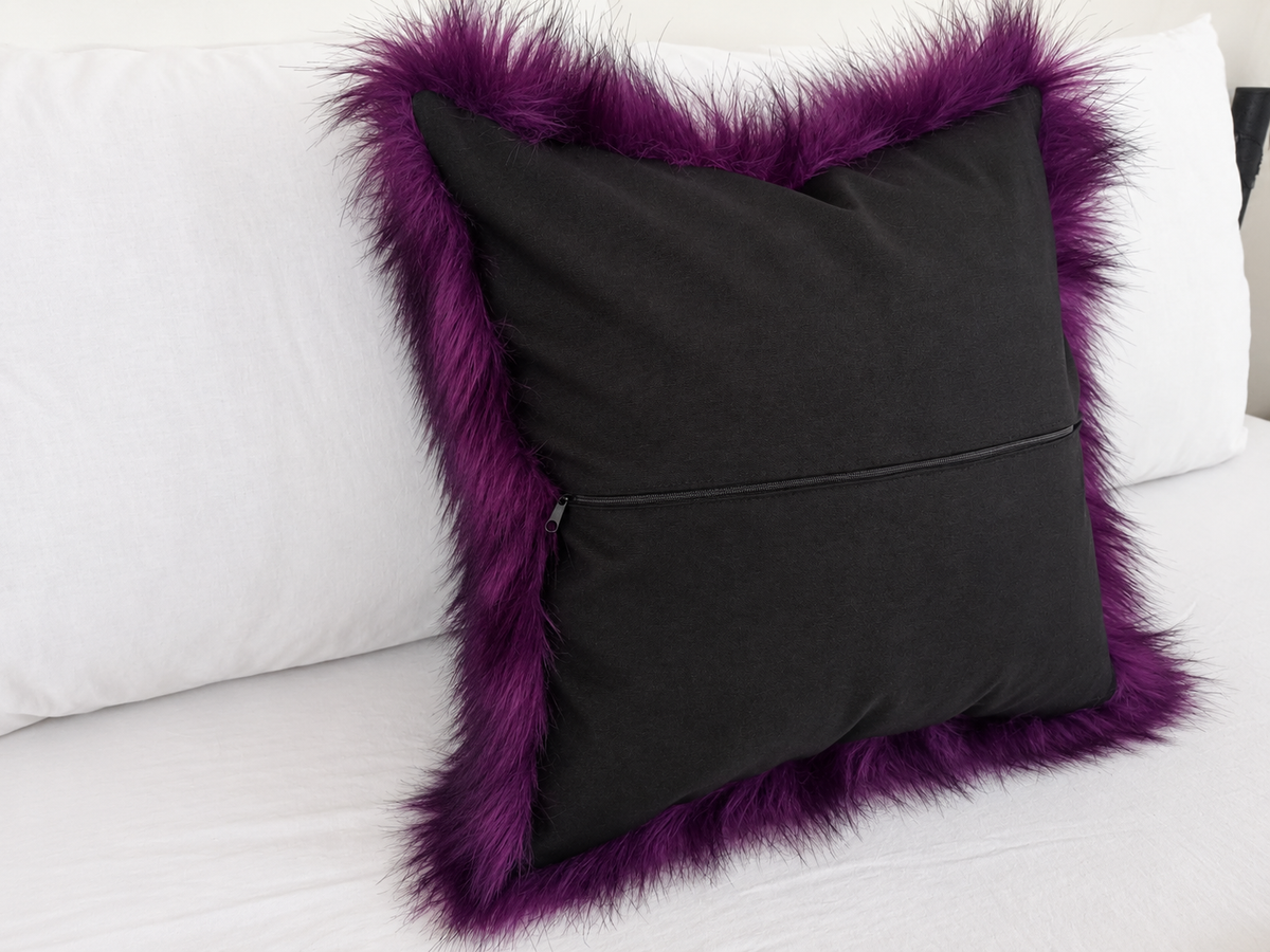 Deep purple faux fur pillow cover with black-tipped long pile, styled on a white sofa for gothic and Halloween home decor