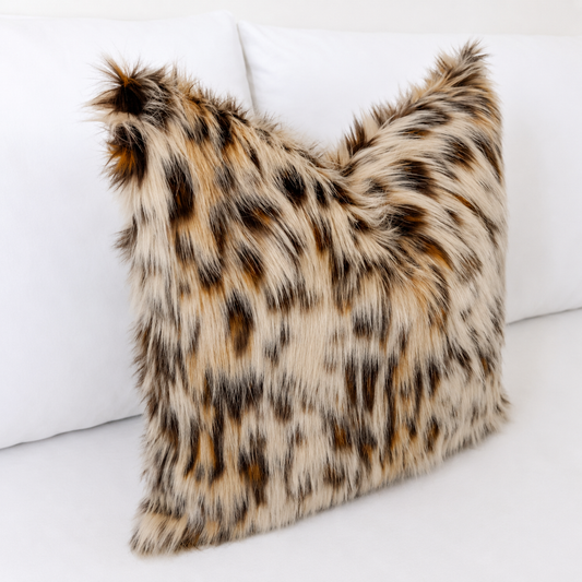 Luxury Leopard Cat faux fur pillow cover with ultra-soft long pile in natural cream, caramel, brown and charcoal tones styled on a white bed.