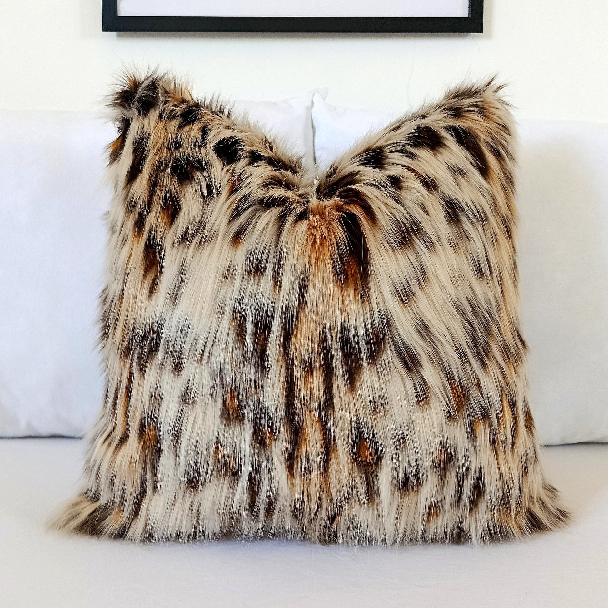 Luxury Leopard Cat faux fur pillow cover with ultra-soft long pile in natural cream, caramel, brown and charcoal tones styled on a white bed.