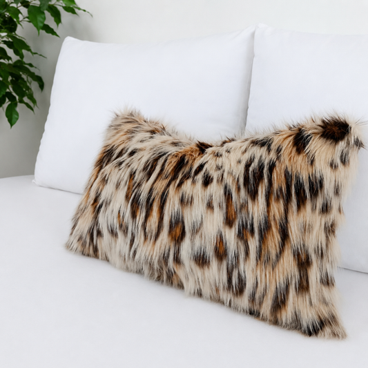 Luxury Leopard Cat faux fur pillow cover with ultra-soft long pile in natural cream, caramel, brown and charcoal tones styled on a white bed.