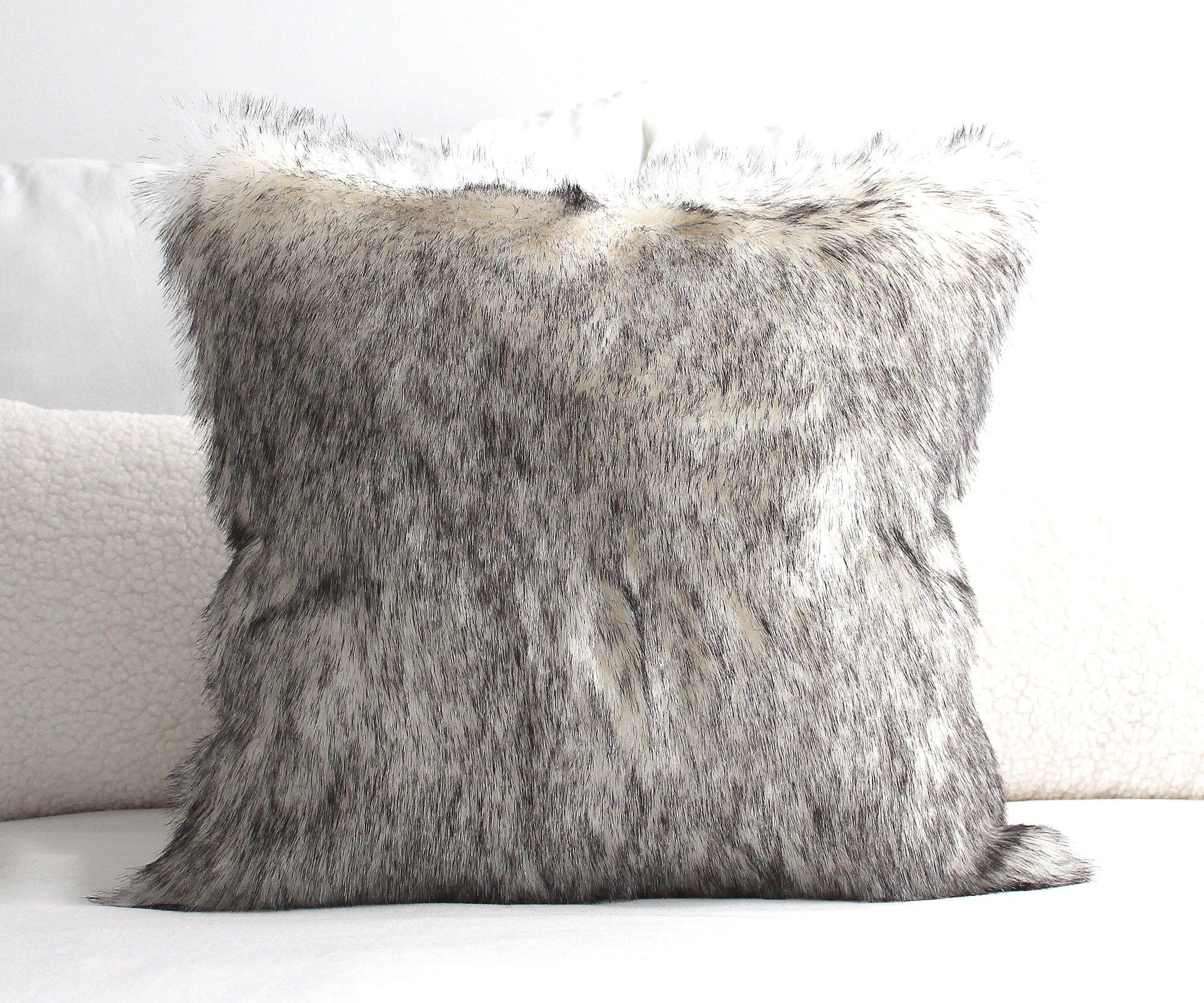Luxury wolf faux fur pillow cover on a sofa with ultra-soft realistic faux fur texture.